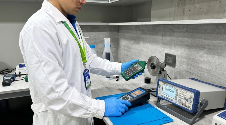T&eacute;cnico de laboratorio comparando un tac&oacute;metro con un generador de frecuencia patr&oacute;n.